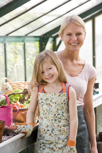 Young girl and woman in greenhouse smiling — Stock Photo, Image