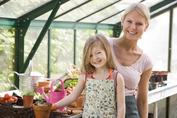 Young girl and woman in greenhouse smiling — Stock Photo, Image
