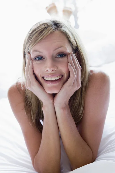 Frau liegt lächelnd im Bett — Stockfoto