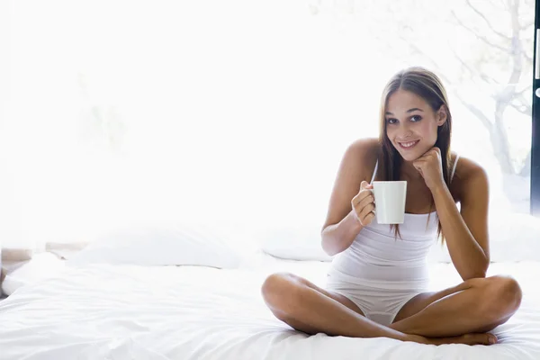 Γυναίκα Που Κάθεται Στο Κρεβάτι Πίνοντας Καφέ Χαμογελώντας — Φωτογραφία Αρχείου