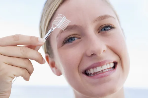 Mujer con cepillo de cejas sonriendo —  Fotos de Stock
