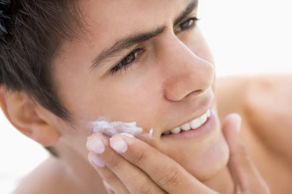 Чоловік одягає крем для гоління, посміхаючись — стокове фото