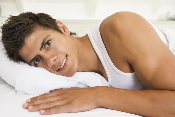 Muž leží v posteli s úsměvem — Stock fotografie