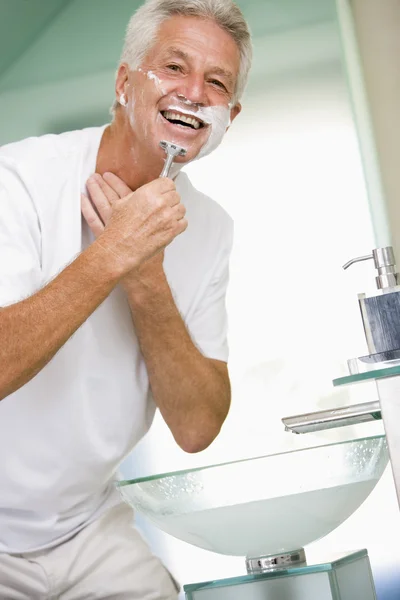 Man in bathroom shaving and smiling — Stock Photo, Image