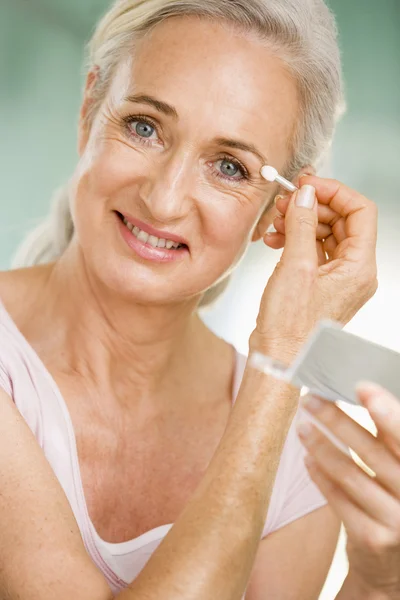 Mujer aplicando maquillaje de ojos y sonriendo — Foto de Stock