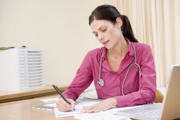 Doutor com laptop escrevendo no consultório do médico — Fotografia de Stock