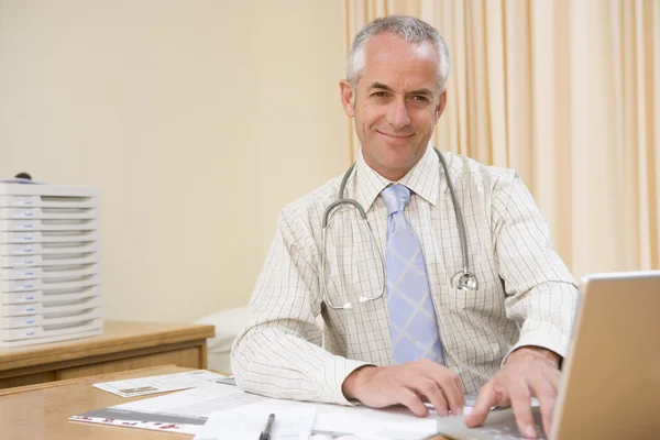 Doctor using laptop in doctor's office smiling — Stock Photo, Image