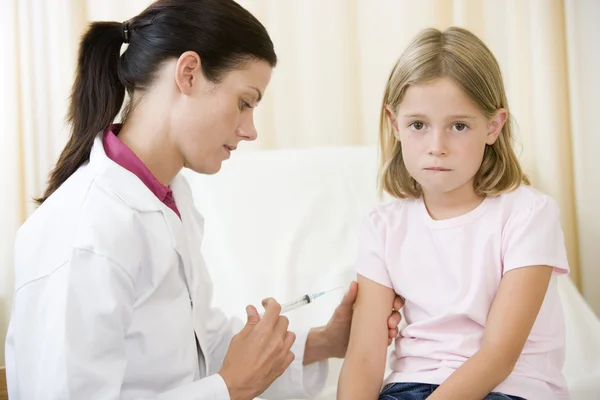 Doctor giving needle to young girl in exam room — Stock Photo, Image