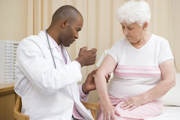 Γιατρός δίνοντας βελόνα στη γυναίκα στο ΕΞΕΤΑΣΤΗΡΙΟ — Φωτογραφία Αρχείου
