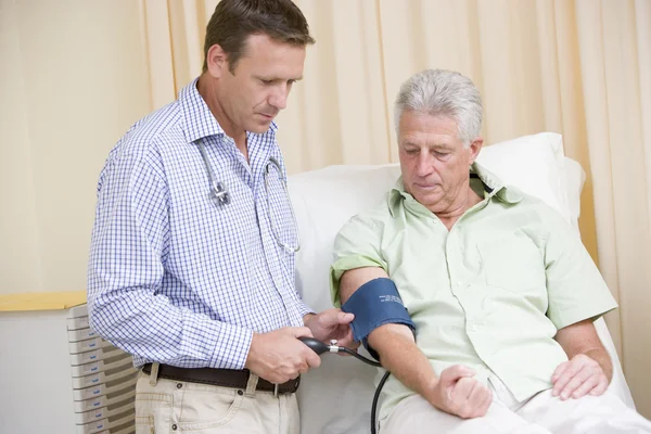 Läkare kontrollera mannens blodtryck i examen rummet — Stockfoto