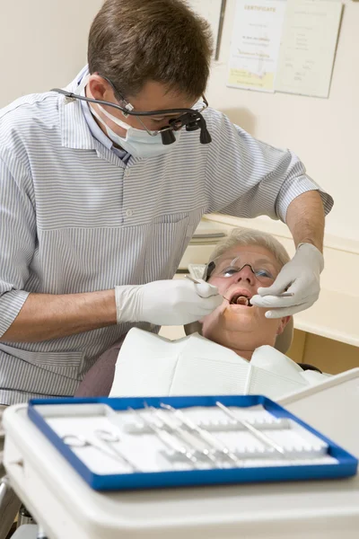 Dentista em sala de exame com mulher na cadeira — Fotografia de Stock