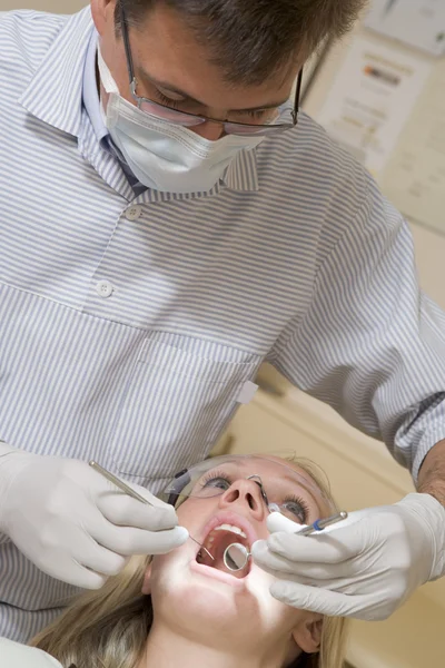 Dentista in sala esami con donna in sedia — Foto Stock