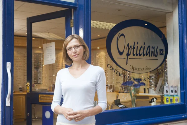 Kvinna som står vid huvudentrén för optiker — Stockfoto