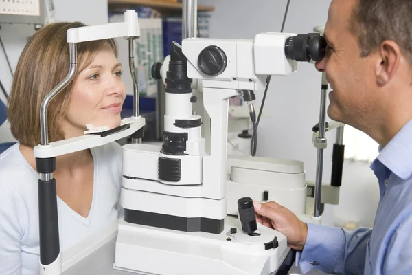 Optometrista in sala esami con donna in sedia — Foto Stock