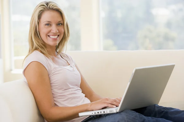 Женщина в гостиной с помощью ноутбука улыбается — стоковое фото