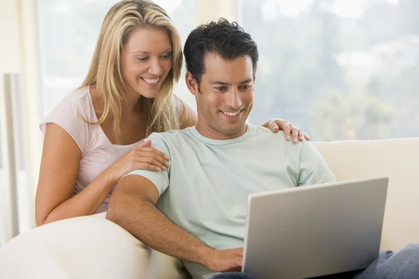 Par i vardagsrummet med laptop leende — Stockfoto