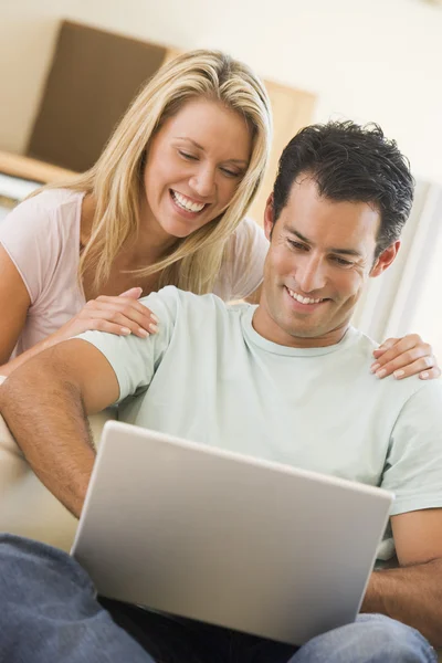 笑みを浮かべてノート パソコンを使用してリビング ルームのカップル — ストック写真