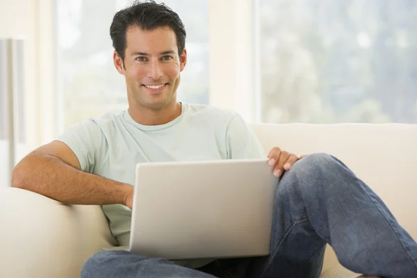 Man in woonkamer met behulp van laptop glimlachen — Stockfoto
