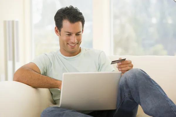 Hombre Sala Estar Utilizando Ordenador Portátil Celebración Tarjeta Crédito Sonriendo — Foto de Stock