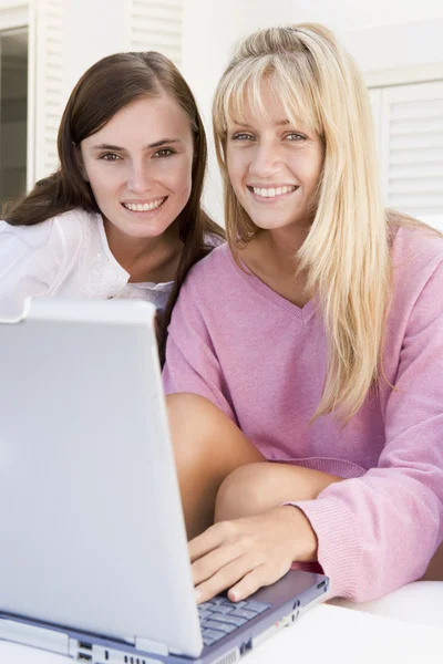 在使用笔记本电脑微笑的露台上的两个女人 — 图库照片