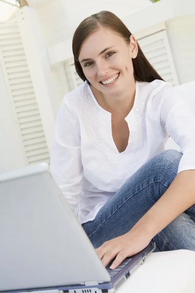 Vrouw op patio met behulp van laptop glimlachen — Stockfoto
