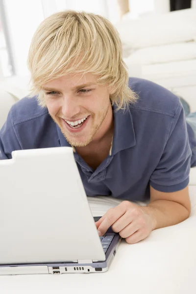 Человек в гостиной с ноутбуком улыбается — стоковое фото