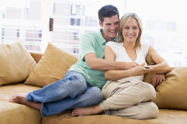 Par i vardagsrum med fjärrkontroll leende — Stockfoto