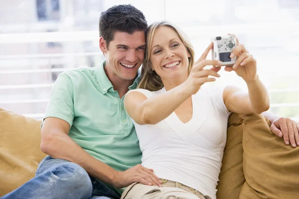 Casal na sala de estar com câmera digital sorrindo — Fotografia de Stock