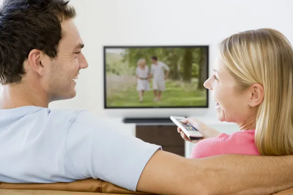 Casal na sala de estar assistindo televisão sorrindo — Fotografia de Stock
