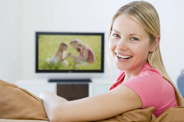 Mulher na sala de estar assistindo televisão sorrindo — Fotografia de Stock
