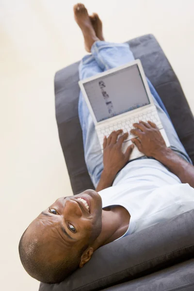 笑みを浮かべてノート パソコンを使用して椅子に坐っていた男 — ストック写真