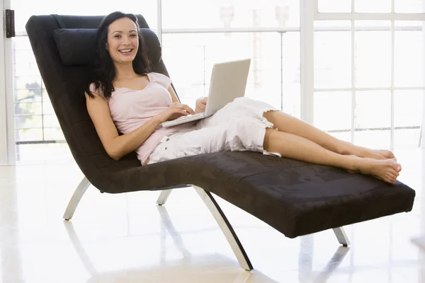 坐在椅子上使用笔记本电脑微笑的女人 — 图库照片