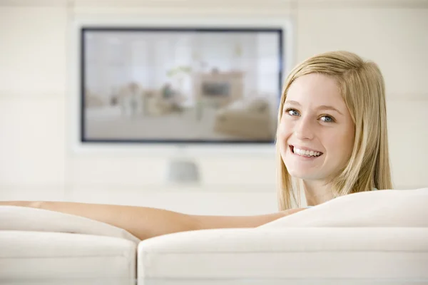 在客厅里看电视微笑的女人 — 图库照片