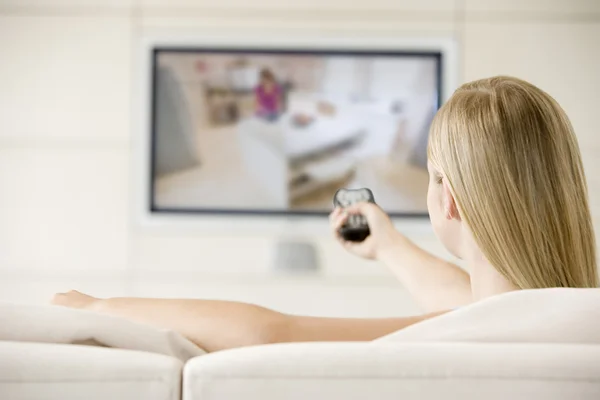 Vrouw in woonkamer televisie kijken — Stockfoto