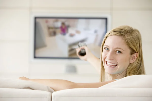 Vrouw in woonkamer kijken televisie glimlachen — Stockfoto