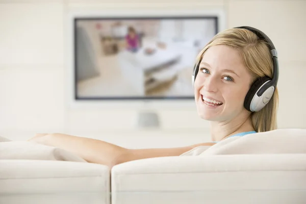 Frau im Wohnzimmer sieht fern und trägt Kopfhörer — Stockfoto