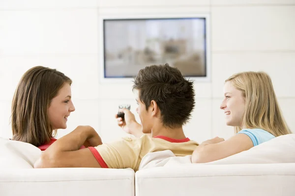 Drie vrienden in woonkamer kijken televisie glimlachen — Stockfoto