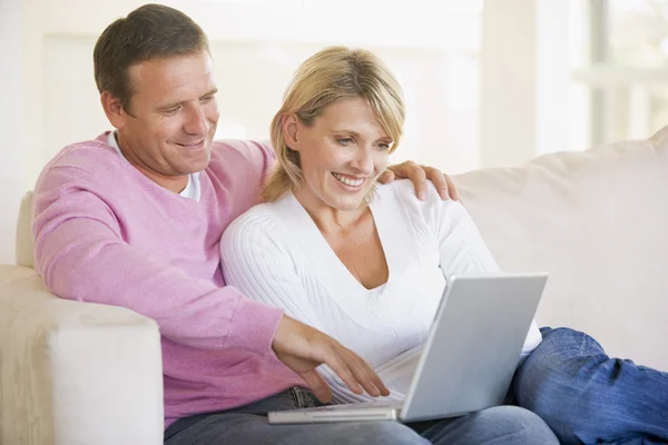 Casal na sala de estar usando laptop e sorrindo — Fotografia de Stock