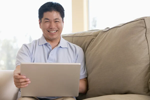 在客厅里使用的便携式计算机和微笑的男人 — 图库照片