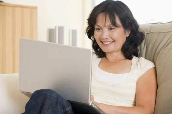 Mujer en la sala de estar usando el ordenador portátil y sonriendo —  Fotos de Stock