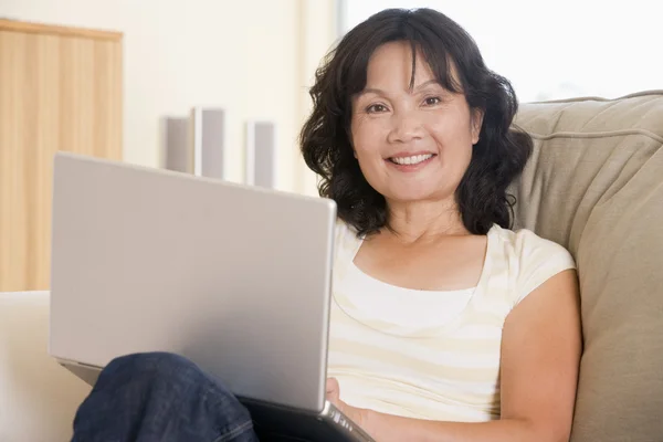 在客厅里使用的便携式计算机和微笑的女人 — 图库照片