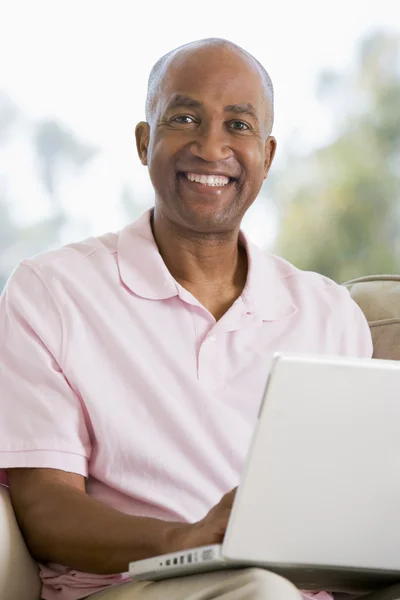 Homem na sala de estar usando laptop e sorrindo — Fotografia de Stock