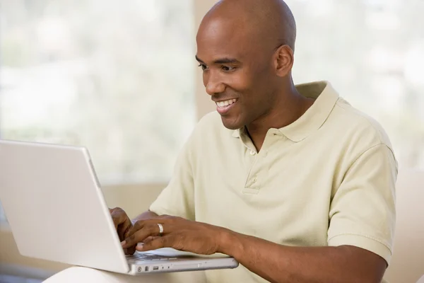 Man in living room using laptop and smiling — Stock Photo, Image