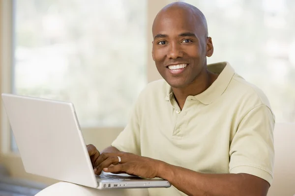 在客厅里使用的便携式计算机和微笑的男人 — 图库照片