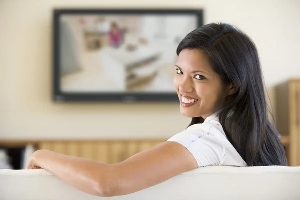 Mulher na sala de estar assistindo televisão sorrindo — Fotografia de Stock
