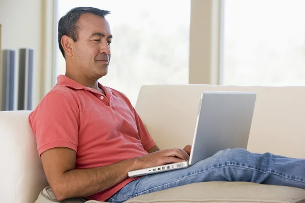 Homem na sala de estar usando laptop e sorrindo — Fotografia de Stock