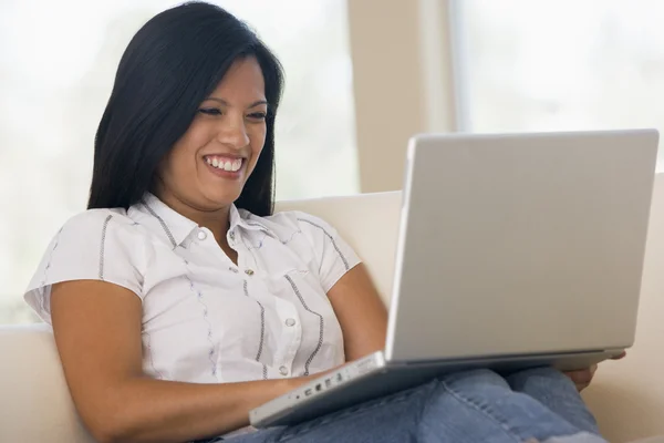 Vrouw in woonkamer met behulp van laptop glimlachen — Stockfoto