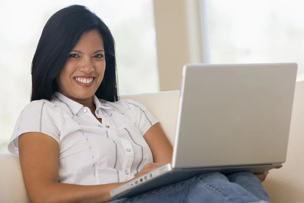 Mujer en la sala de estar con el ordenador portátil sonriendo — Foto de Stock