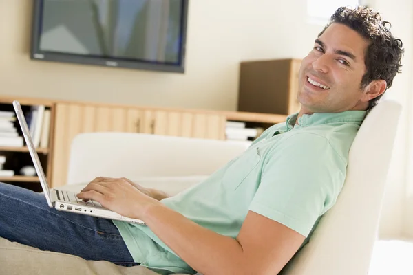 在使用笔记本电脑微笑的客厅里的男人 — 图库照片