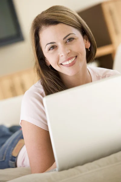 Γυναίκα στο σαλόνι, χρησιμοποιώντας φορητό υπολογιστή χαμογελώντας — Φωτογραφία Αρχείου